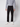 A person models PROJEK RAW’s Men’s Bungee Loose Pant in black, paired with a light gray zip-up sweater and white sneakers, standing against a plain white background. The image highlights the casual style from shoulders down.