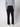 A person faces away, wearing a PROJEK RAW Men’s Bungee Loose Pant in black with a light gray long-sleeve shirt and white shoes, standing against a plain light background—an ideal casual look.