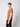 A young man with short light brown hair stands sideways to the camera, wearing a PROJEK RAW Mens Liquid Cotton Short Sleeve T-shirt in brown and black pants, against a plain light grey background.