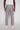 Dressed in Projek Raw’s LUC-GREY linen drawstring pants and a white tee, a person stands with their back to the camera against a plain white background, highlighting an effortlessly relaxed summer look.