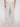 A person is shown from the back wearing Projek Raw’s LUC-NATURAL vacation-ready linen drawstring pants in light beige, paired with white sneakers. The summer pants feature two back pockets with button closures, set against a plain white background.