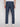 A person is shown from the back, standing against a light background, wearing Projek Raw LUC-NAVY linen drawstring pants with two buttoned back pockets and white shoes. The vacation-ready pants are in blue.