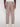 A person is seen from the back wearing Projek Raws LUC-TABAC light brown linen drawstring pants with two buttoned back pockets and white sneakers, offering a relaxed summer style against a plain white background.