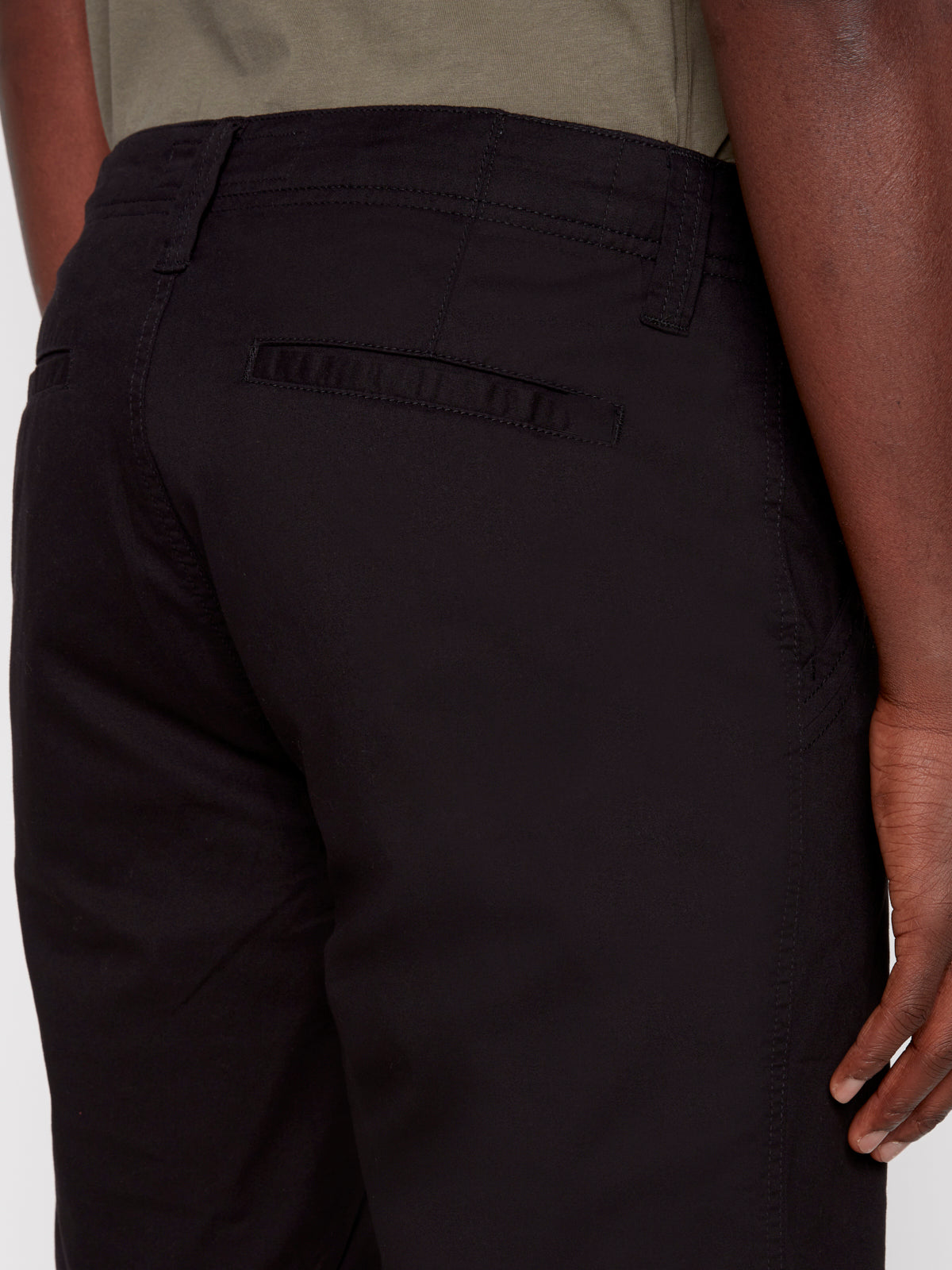 A close-up of a person wearing Projek Raws GUSTAVE-BLACK pants, highlighting the back pocket and side seam, with their hand resting by their side.
