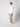 A man stands in a studio wearing a white quarter-zip sweater, PROJEK RAW Mens Stretch Bungee Cargo Pant, and white sneakers. He faces left with a neutral expression against a plain light gray background.