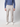 A person models PROJEK RAW Mens Bungee Relaxed Chino Pant in light beige with a blue button-up shirt and white sneakers against a plain light background. The head is not visible in the image.