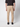 A person stands facing away, wearing a black short-sleeve shirt, PROJEK RAW Men’s Stretch Bungee Cargo Jogger with elastic cuffs, and black shoes, against a plain light background.