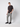 A man stands against a light grey background, wearing a black short-sleeve t-shirt and PROJEK RAW Men’s Stretch Bungee Cargo Jogger in light grey, paired with black sneakers. One hand is in his pocket as he looks directly at the camera.