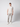 A young man stands against a plain light background wearing a light beige t-shirt, PROJEK RAW Mens Bungee Loose Cargo Pant in light gray, and white sneakers. He faces the camera with a neutral expression and relaxed posture.