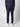 A person stands facing away, wearing PROJEK RAW’s Men’s Relaxed Chino Pant in dark navy with a matching sweater and white sneakers against a plain light background.