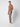 A man stands sideways against a plain light background in a brown turtleneck, white sneakers, and PROJEK RAW Men’s Houndstooth Bungee Tailored Pant, one hand in his pocket and a neutral expression.