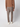 A person stands facing away, wearing a brown long-sleeve top, PROJEK RAW Men’s Houndstooth Bungee Tailored Pant, and white sneakers against a plain light-colored background.