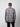 A man stands with his back to the camera, wearing a gray PROJEK RAW Mens Long Sleeve Plaid Button-up Shirt and black pants against a plain light gray background.