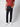 A person, visible from the shoulders down, wears a rust t-shirt, white sneakers, and PROJEK RAW Mens 5 Pocket Slim Fit Jean in indigo wash against a plain light gray background.