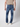 A person in PROJEK RAW Mens 5-Pocket Straight Fit Jeans, a beige t-shirt, and white shoes stands with their back to the camera against a plain light background.