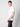 A young man in a classic fit PROJEK RAW Mens Short Sleeve Crewneck T-shirt and dark jeans stands against a light gray background, facing sideways with his left hand in his pocket and looking at the camera.