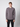 A young man with short brown hair models the PROJEK RAW Mens Long Sleeve Crewneck T-shirt and black pants, standing facing forward against a light gray background—a true mens wardrobe staple.