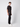 A young man stands sideways against a light gray background, wearing a loose black T-shirt, PROJEK RAW Mens 5-Pocket Straight Fit Jean in black rinse, and white sneakers.