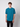 A young man with curly brown hair stands against a light gray background, wearing a PROJEK RAW Mens Short Sleeve Crew T-shirt in teal and black pants, facing forward with a neutral expression.