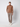 A man stands against a light background, wearing a brown turtleneck sweater, PROJEK RAW Men’s Houndstooth Bungee Tailored Pant, and white sneakers. His hands are in his pockets and he looks directly at the camera.