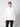 A young man wearing the PROJEK RAW Mens Zip Mock Neck Sweater in white and black pants stands against a plain light background, looking directly at the camera with a neutral expression.