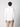 A man faces away from the camera, wearing the PROJEK RAW Mens Zip Mock Neck Sweater in white and beige cargo pants against a plain light background.