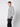 A young man with light brown hair wears the PROJEK RAW Mens Cable Knit Mock Neck Sweater in gray and white, paired with black pants, standing sideways against a plain white background.