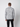 A man faces away from the camera, wearing the PROJEK RAW Mens Cable Knit Mock Neck Sweater in light gray and black marled knit with black pants, set against a plain light gray background.