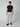 A man stands against a plain light background wearing a black short-sleeve t-shirt, PROJEK RAW Mens Solid Bungee Cargo Pant with an elasticized waistband in light gray, and black slip-on shoes, looking straight ahead with a neutral expression.