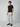 A man stands against a plain background, wearing PROJEK RAW Mens Solid Bungee Cargo Pant in light grey with an elasticized waistband and pockets, paired with a black short-sleeve t-shirt and black slip-on shoes, looking forward neutrally.