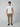 A man faces forward in a plain white tee, PROJEK RAW Mens Solid Bungee Cargo Pant in tan, and black slip-on shoes against a light gray background, creating a modern streetwear style.