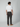 A man faces away from the camera, wearing a white T-shirt and PROJEK RAW Mens Solid Bungee Relaxed Chino Pant with tan shoes against a plain light gray background.
