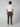 A man faces away in a white short-sleeve shirt, PROJEK RAW Mens Solid Bungee Fashion Chino Pant (tailored fit), and beige slip-on shoes, set against a plain light gray background.