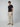 A man with short curly hair and a neutral expression stands against a plain background, wearing PROJEK RAW Mens Bungee Loose Cargo Pant with an elastic waistband and side pockets, a black t-shirt, and tan sneakers.