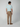 A man faces away from the camera, wearing a light blue short-sleeve t-shirt and PROJEK RAW Mens Solid Bungee Relaxed 5-Pocket Pant with an elastic waistband, plus brown shoes, against a plain light background.