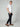 A man stands sideways with his hands in his pockets, wearing a white short-sleeve t-shirt, PROJEK RAW MENS CHINO SIGNATURE WOVEN PANT in black, and brown loafers against a plain light gray background.