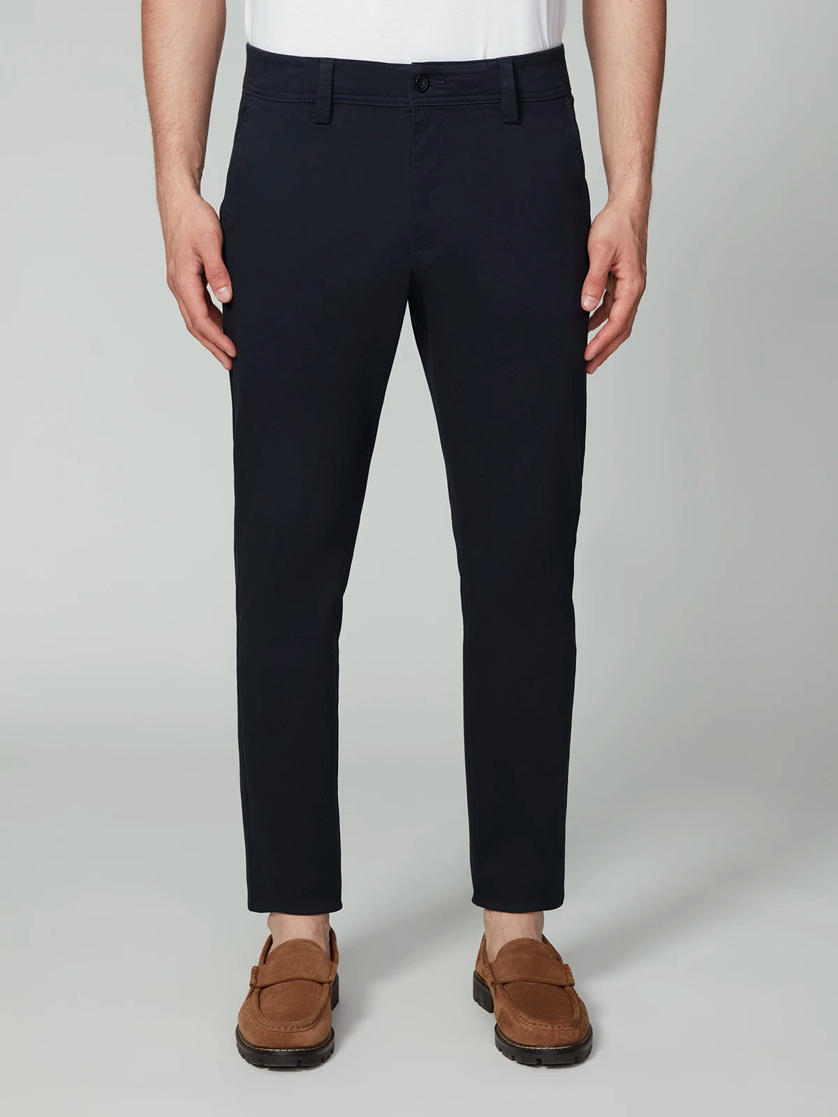 A man in PROJEK RAW MENS CHINO SIGNATURE WOVEN PANT (navy), paired with a white shirt and brown loafers, stands against a plain light background.