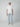 A young man stands against a plain background, wearing a beige cap, plain white t-shirt, PROJEK RAW MENS 5-POCKET ATHLETIC FIT JEAN in light blue stretch fabric, and beige slip-on shoes. He faces forward with a neutral expression.