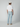 A man faces away from the camera, wearing a white t-shirt, beige sneakers, a beige baseball cap, and PROJEK RAW MENS 5-POCKET ATHLETIC FIT JEAN made from stretch fabric, against a light gray background.