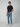 A young man stands against a light gray background, wearing a black t-shirt and PROJEK RAW NIKKO MENS 5-POCKET SLIM FIT JEAN, one hand in his pocket, looking forward with a neutral expression.