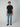 A young man stands against a light gray background, wearing a black t-shirt, brown loafers, and PROJEK RAWs NIKKO MENS 5-POCKET SLIM FIT JEAN. He faces forward with a neutral expression and relaxed arms at his sides.