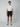 A person stands facing forward against a plain background, wearing a white short-sleeve shirt, gray sneakers, and PROJEK RAW Mens 5-Pocket Solid Bungee Shorts with an elasticized waistband.