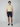 A young man faces forward wearing a short-sleeve beige knit polo, PROJEK RAW Mens 5-Pocket Solid Bungee Shorts in dark navy, and navy slip-on shoes against a plain light gray background.