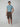 A young man stands against a light gray background wearing PROJEK RAW Mens Solid Bungee Pull-on Cargo Shorts with pockets, a light blue t-shirt, and white sneakers. One hand is in his pocket as he looks directly at the camera.