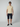 A man stands against a plain background wearing sunglasses, a light beige short-sleeve polo shirt, PROJEK RAW Mens Solid Bungee Capri Cargo Shorts 13 Inseam, and dark slip-on shoes. His arms hang relaxed at his sides.