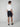 A person faces away from the camera wearing a white t-shirt, PROJEK RAW Mens Texture Bungee 5-Pocket Shorts in navy with an elastic waistband, and navy slip-on shoes, set against a plain light grey background.
