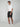 A man stands against a plain background wearing a white tee, PROJEK RAW Mens Texture Bungee Chino Short 9 Inseam made from stretch fabric, and white sneakers—his relaxed look is perfect for your summer wardrobe.