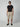 A man stands against a plain background, wearing black sunglasses, a black t-shirt, PROJEK RAW MENS PULL-ON CARGO SHORT with an elastic waistband in beige, and black slip-on shoes. He faces forward with a neutral expression.