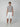 A young man stands against a light gray background, wearing a fitted light gray t-shirt, PROJEK RAW MENS CAPRI CARGO SHORT in white, and white sneakers. He faces forward with a neutral expression and relaxed arms at his sides.