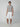 A young man faces forward against a plain background, wearing a fitted gray tee, white sneakers with beige soles, and PROJEK RAW MENS CAPRI CARGO SHORT made from durable fabric, with arms relaxed by his sides.